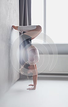 Slim woman in handstand against wall