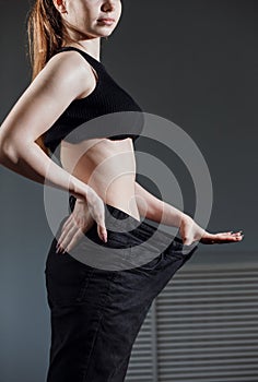 Slim Woman with healthy thin body,showing her old jeans after successful diet.
