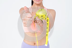 Slim woman holding apple with measuring tape