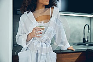 Slim woman holding a glass of cucumber drink