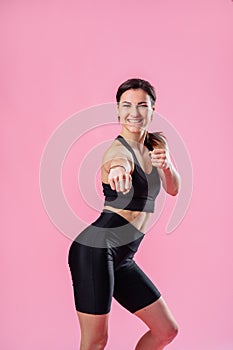 Slim woman is kicking the air, with hand. Boxing. Athletic sportswoman doing boxing exercises, making a direct kick. Photo of a