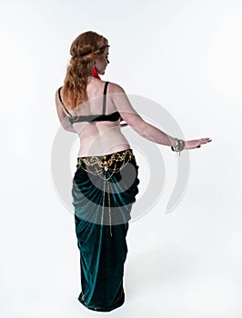 Slim woman with long hair in decorated traditional green belly costume with top and skirt dancing with outstretched hands