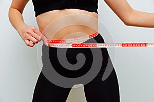 Slim woman measures her waistline with measuring tape. Healthy body shaping weight loss concept