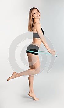 Slim woman measuring her hips on light background. Perfect body