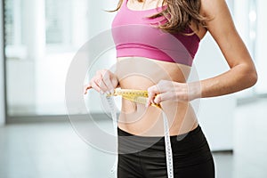 Slim woman measuring her thin waist