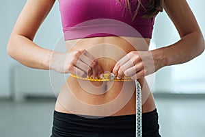 Slim woman measuring her thin waist