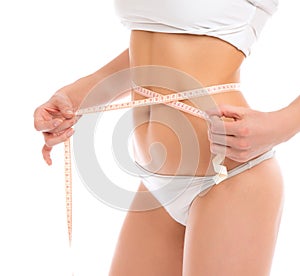 Slim woman measuring waist with tape measure