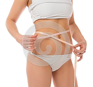 Slim woman measuring waist with tape measure