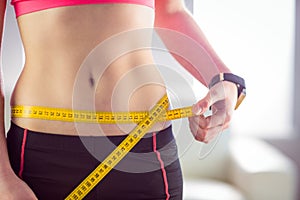 Slim woman measuring waist with tape measure