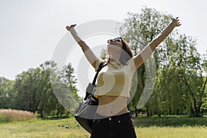 Slim woman with raised arms breathing air, enjoying of nature. Female travelling with backpack, relaxing after hiking.