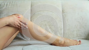 A Slim Woman Sitting Rubs Cream into her Leg, Moisturizing and Massaging the Skin. The Girl Takes Care of her Body.