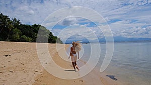 Slim woman smiling and having fun at beach. Summer video portrait of young beautiful blonde female running on sandy