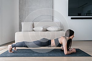 Slim woman standing in plank during training at home