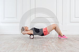 Slim woman using foam roller in gym to workout to remove the pain, stretching and massaging muscles.