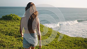 Slim woman walking to banawa beach cliff edge