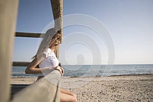 Slim woman wear bikini sitting on wooden guard tower