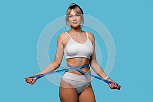 Slim woman in white underwear measure waist with tape