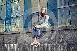 Slim young girl in casual clothes sitting against business cente