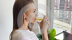 Slim young woman drinking lemon detox water in slow motion enjoying taste