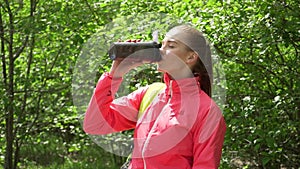 Slim young woman drinking water after training. Woman athlete takes a break, she drinking water, out on a run on a hot