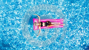 Slim young woman lying on pink air mattress in the pool
