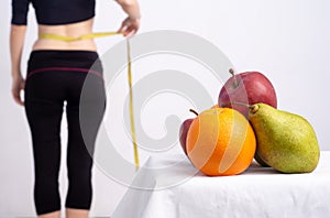 Slim young woman measuring her thin waist with a tape measure