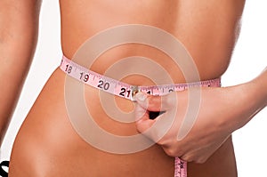 Slim young woman measuring waist