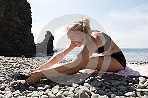 Slim young woman trains on shingle beach