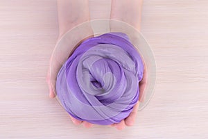 Slime in palms.Purple big  glue,Close up of hands holding slime. View from above.Lght background