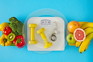 Flat lay composition of scales, dumbbells and tape measure, plate with fruits and vegetables on blue background