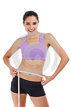 Slimming down for summer. Three quarter length shot of an attractive young woman in gym clothes measuring her waist.