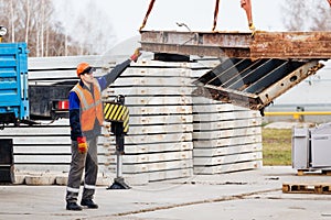 Slinger in helmet and vest controls unloading of metal structures on construction site.