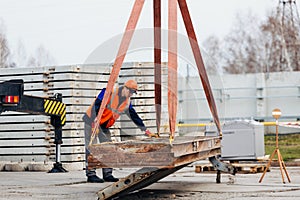 Slinger in helmet and vest controls unloading of metal structures on construction site.