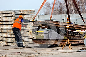 Slinger in helmet and vest controls unloading of metal structures on construction site.