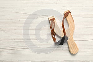 Slingshot with leather pouch on white wooden background, top view. Space for text