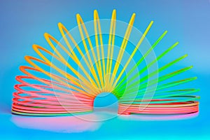 Slinky, plastic toy with colors of the rainbow, colorful children`s spring on a blue background