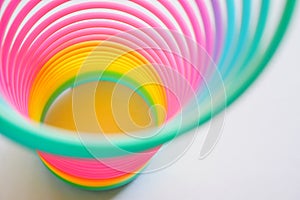 Slinky, plastic toy with colors of the rainbow, colorful children`s spring on a blue background.