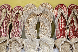 Slippers made up of jute against yellow board