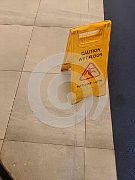 Slippery warning board sign on the top of the floor that have been mopped photo
