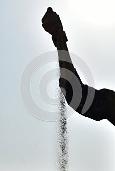 Slipping off sand from black shaded hand and arm with sky background at Jammu city, Jammu and Kashmir, India