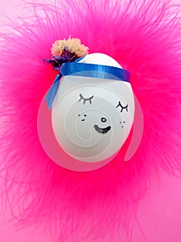 Slipping and smiling face painted on egg on pink background
