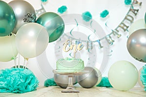 sliver, blue and white decoration for a 1st birthday cake smash studio photo shoot with balloons, paper decor, cake and