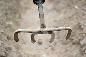 A sliver or rake with four iron prongs was raised above the ground in close-up