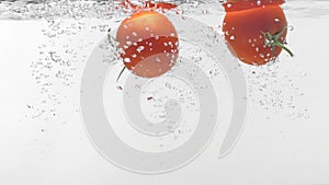 Slo-motion two tomatoes falling into water