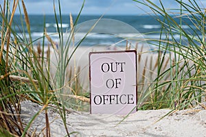 The slogan \'out of office\' in the sand dunes at the beach.