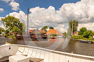 Sloop in front of an old sailing boat in a canal in the Dutch village of Heeg, Friesland, The Netherlands