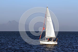 Sloop sailboat on a quiet sea in open waters.