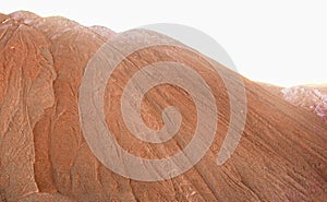 The slope of a brown mountain made of clay and industrial waste against a light sky.