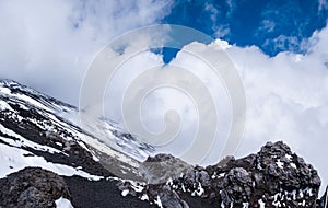 Slope of Mount Etna crater, Sicily island in Italy. Close view of volcanic lava rocks and stones covered with snow in