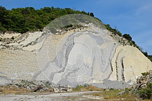 slope of the mountain with layers of sedimentary rocks. Vertically located sedimentary rocks on collapsing hillside